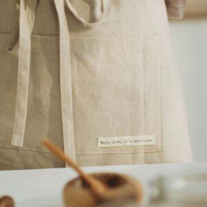 Beige apron tied around waist in a soft kitchen ambiance, promoting culinary warmth.